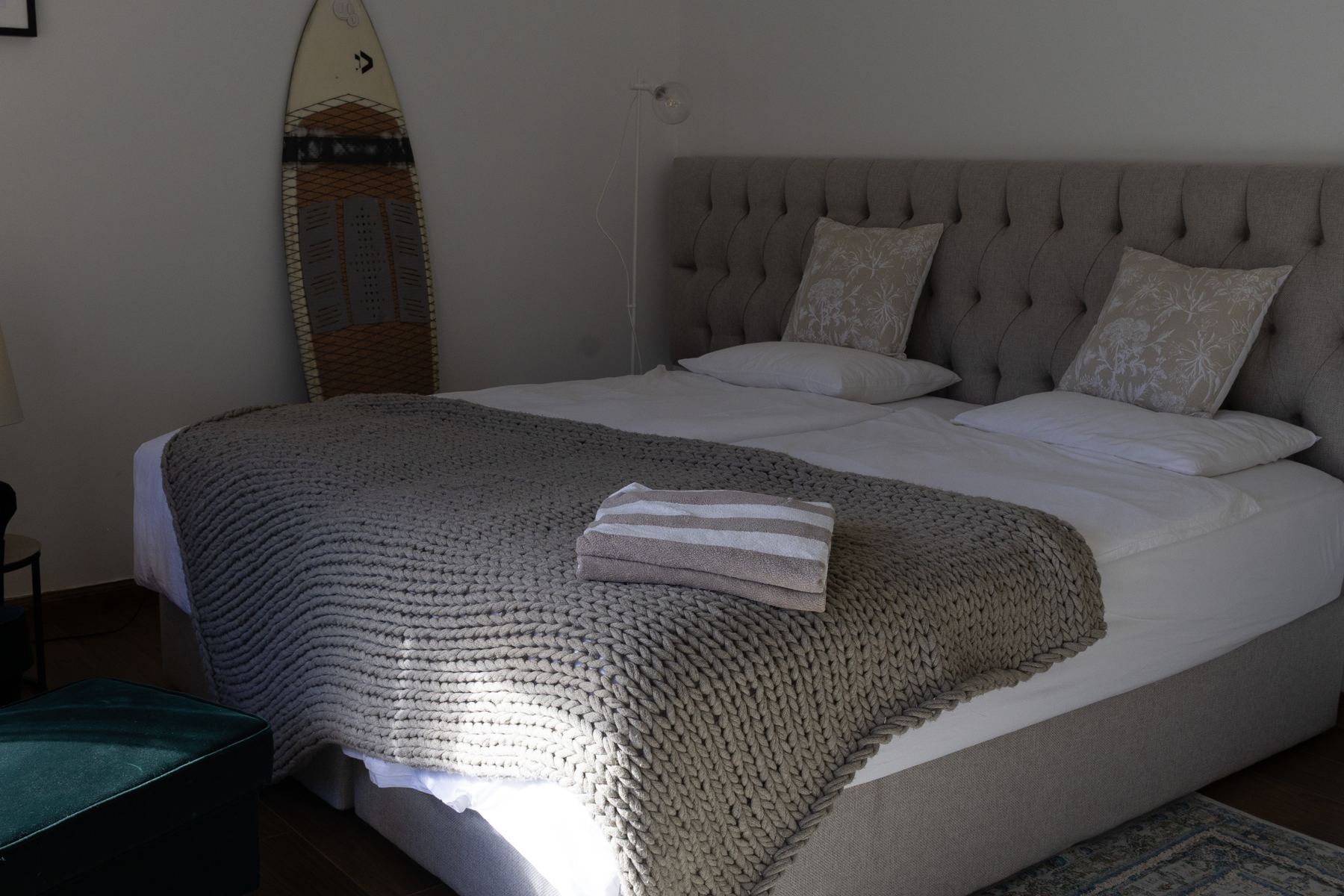 Guest bedroom with a grey headboard and surfboard