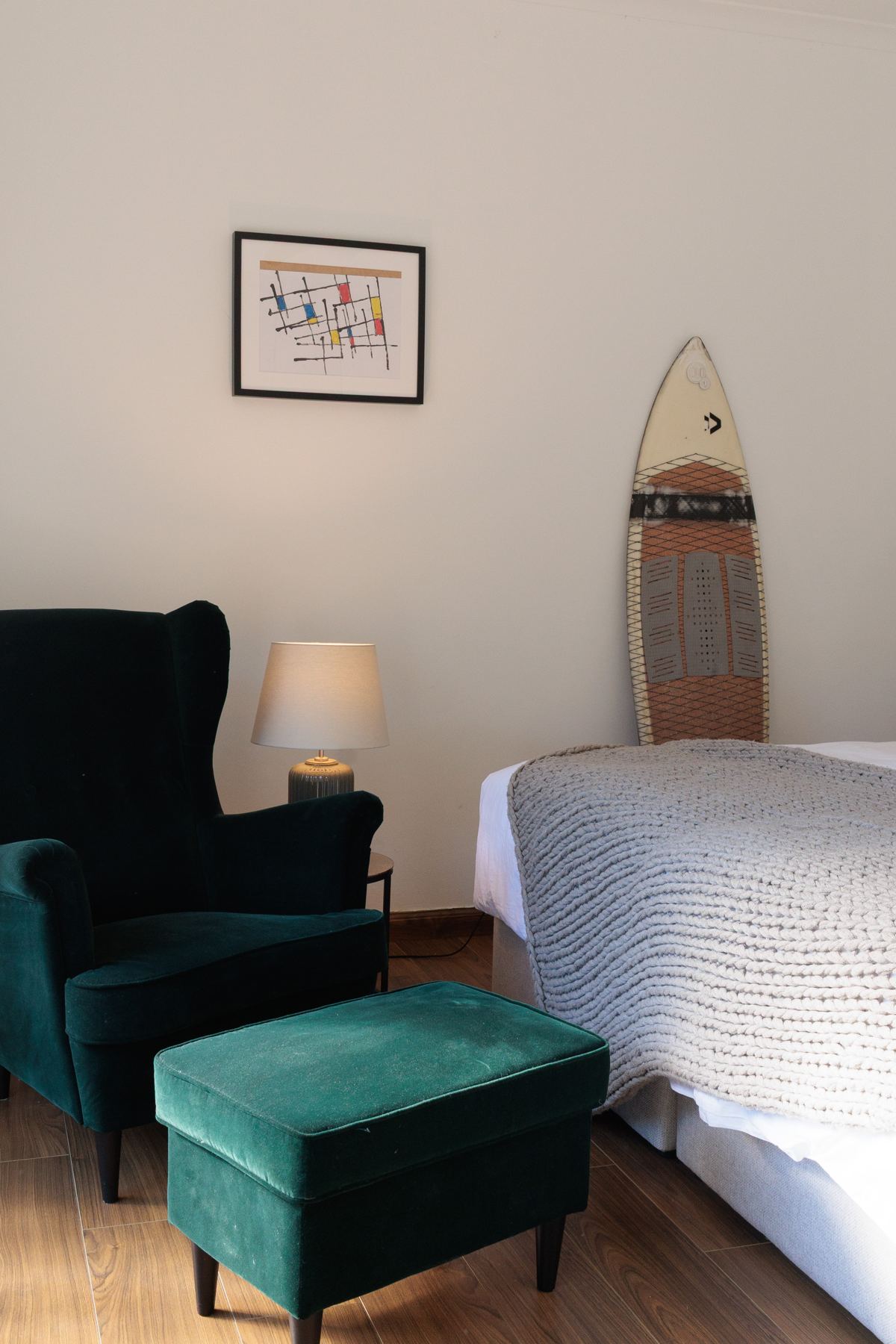 Guest bedroom with a green armchair and surfboard