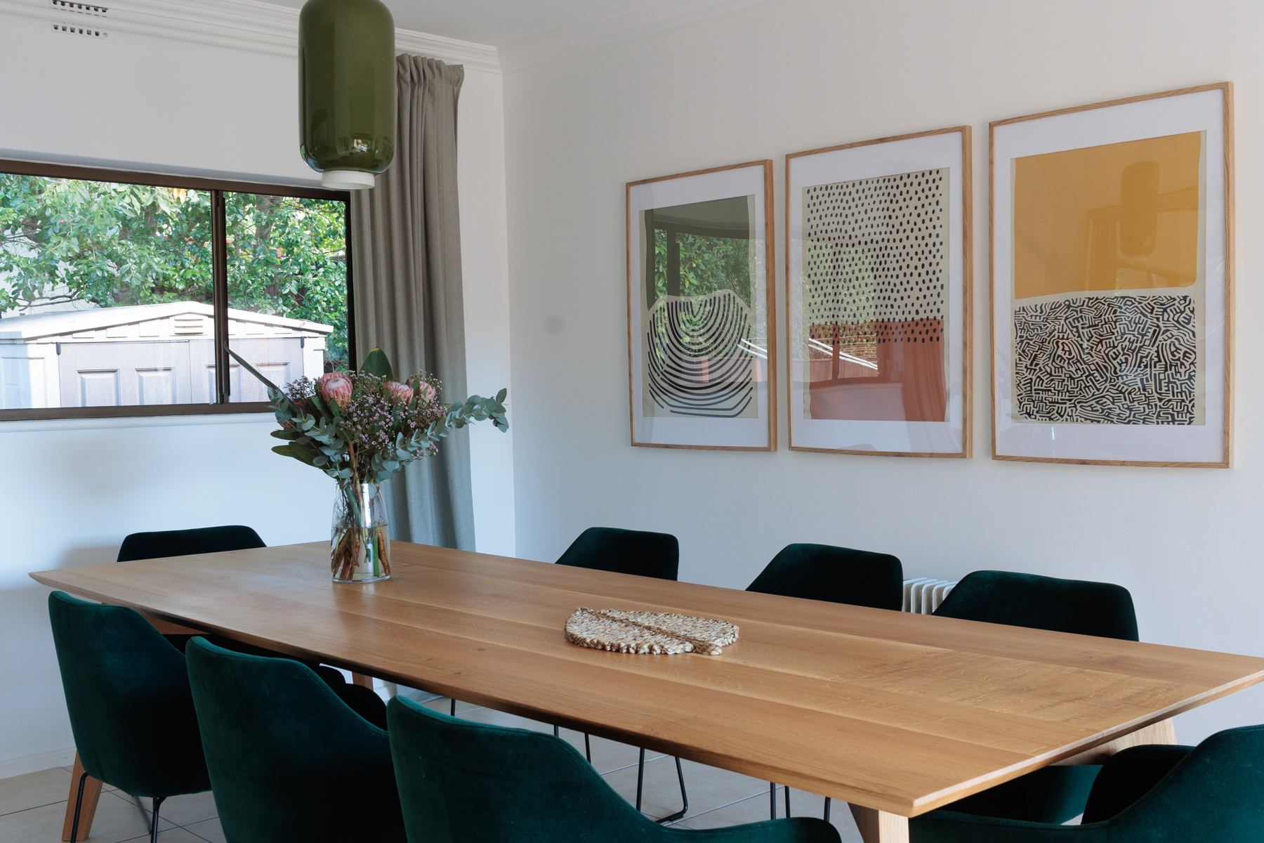Long dining table beneath framed prints